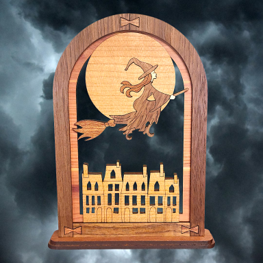 A wooden silhouette of a witch on a broomstick flying over a spooky skyline.