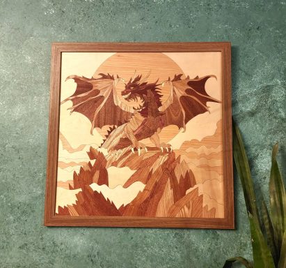 Wooden artwork of a dragon flying over mountains against a sunset backdrop.