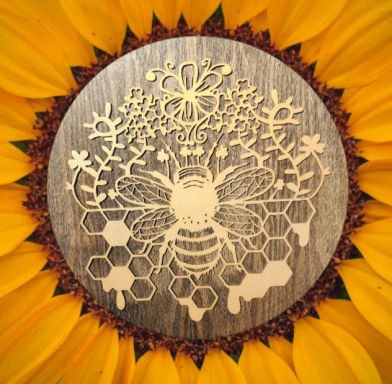 Bees and honeycomb design on a wood circle, surrounded by sunflower petals.